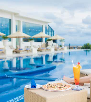 Lady relaxing on a sunbed at Honey Beach while enjoying fresh juice and pizza