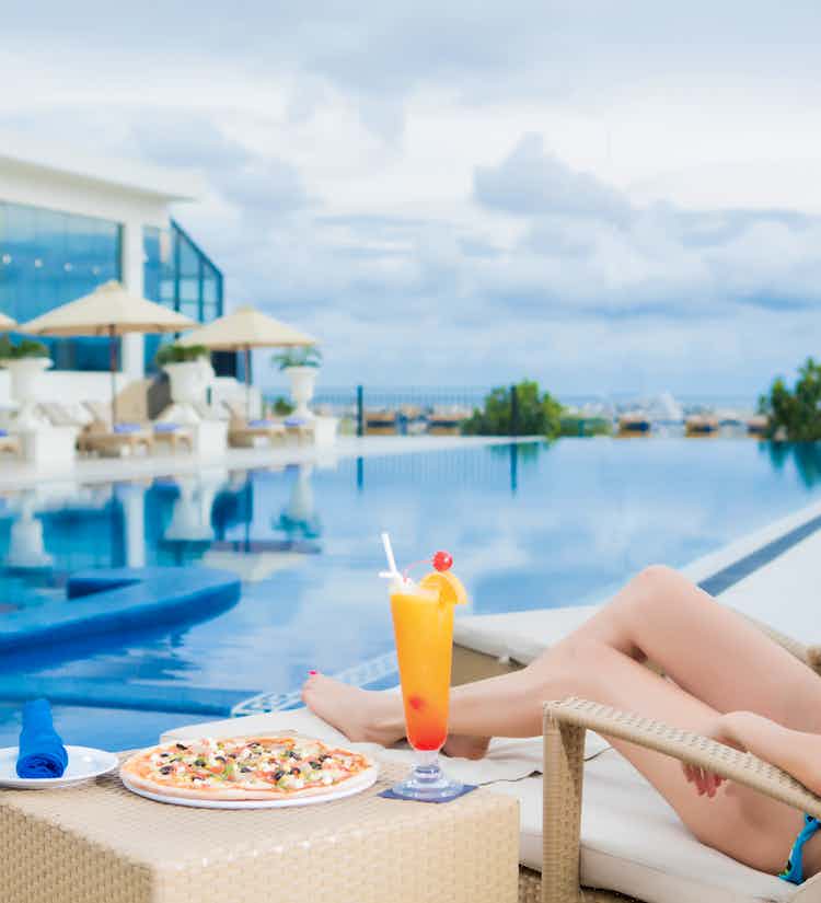 Lady relaxing on a sunbed at Honey Beach while enjoying fresh juice and pizza