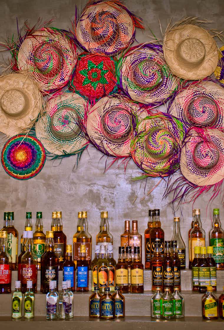 Arrack bottle collection with colorful hats decorating the wall at the Taven bar
