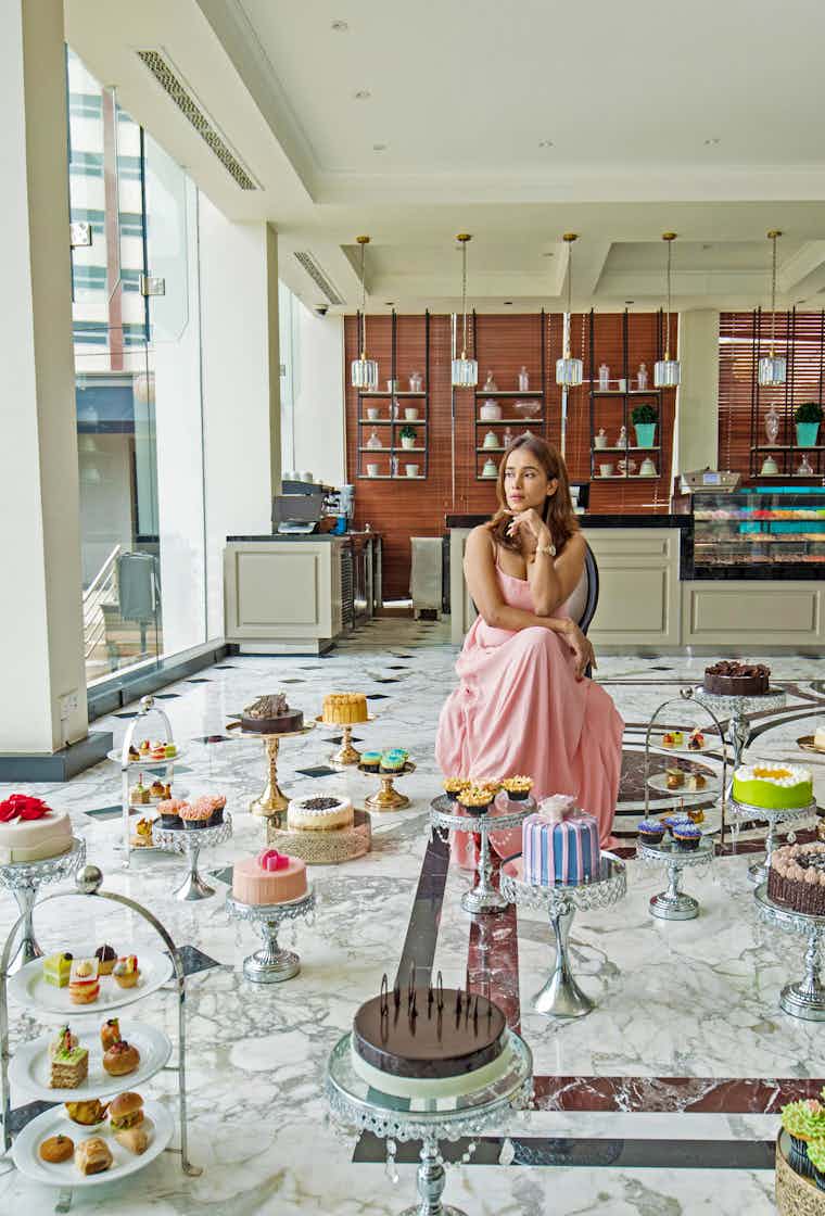 Lady sitting in front of a variety of cakes at The Kingsbury Hotel