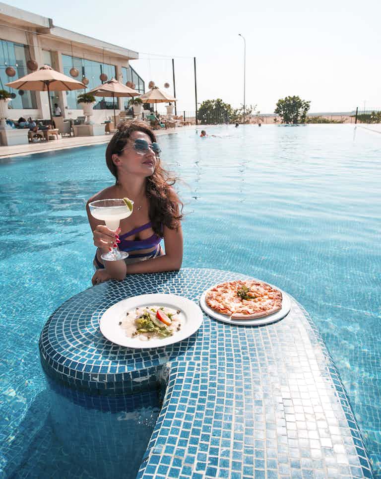Lady enjoying a margarita and pizza at the Kingsbury Pool