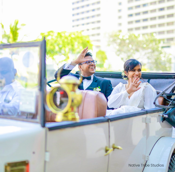Wedded couple leaving The Kingsbury Hotel in a white vintage car
